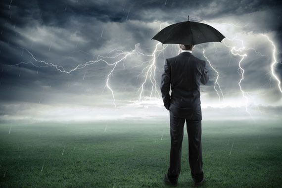 Homme d'affaires devant un orage et qui se protège avec un parapluie.