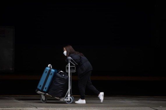 Une femme marche avec un porte bagage 
