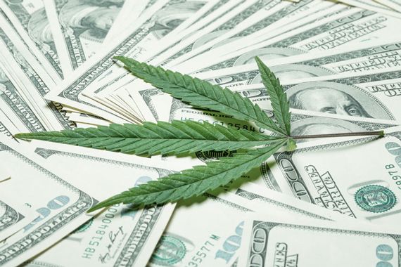 Une feuille de cannabis sur un lit de billets américains