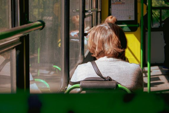 Une dame de dos assise dans un autobus.