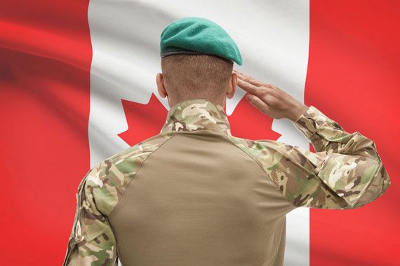 Un militaire de dos devant un drapeau canadien.