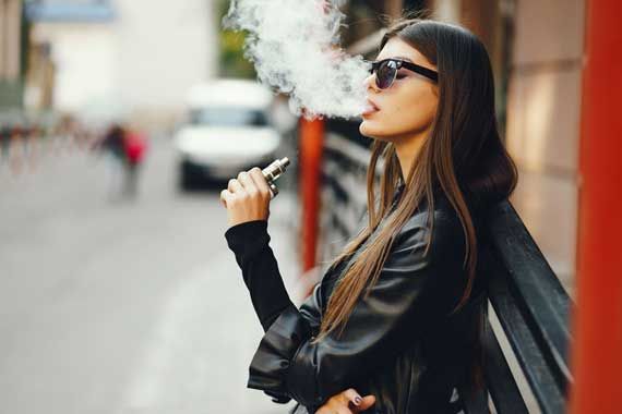 Une femme qui fume une cigarette électronique.
