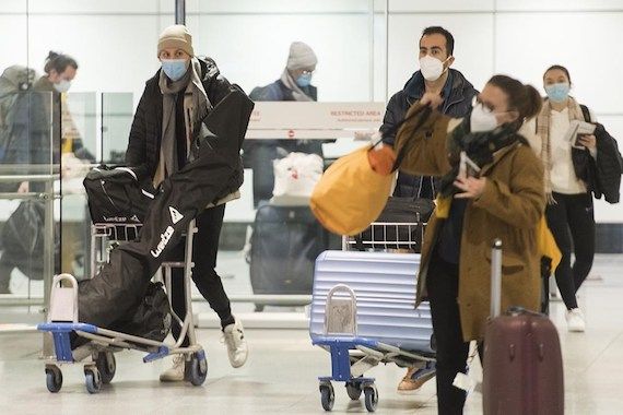 Des voyageurs marchent à l'aéroport avec leurs baggages.