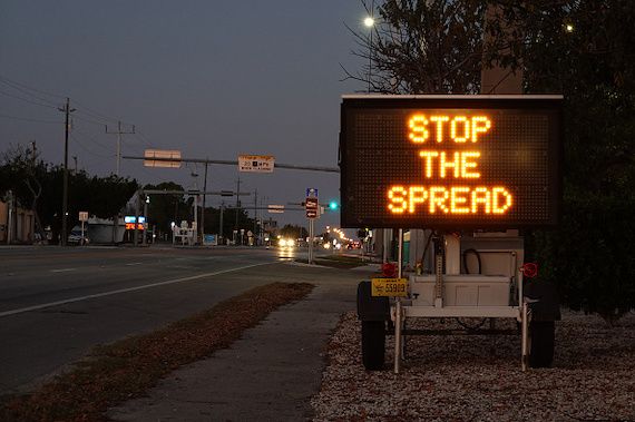 Sur une affiche en bordure de route est écrit «stop the spread».