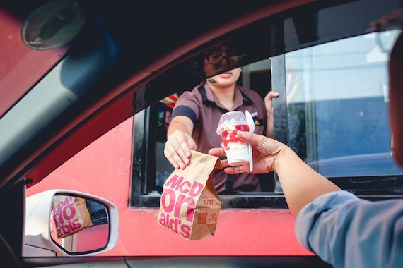 Une employée de McDonald's tend un sac à la commande à l'auto.