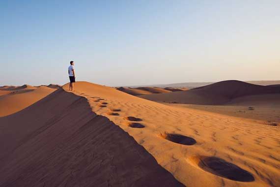 Un homme au sommet d'une dune, dans le désert.