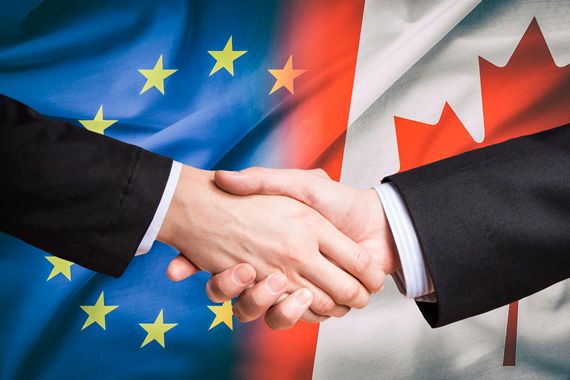 Devant des drapeaux du Canada et de l'Europe, deux personnes se serrent la main.