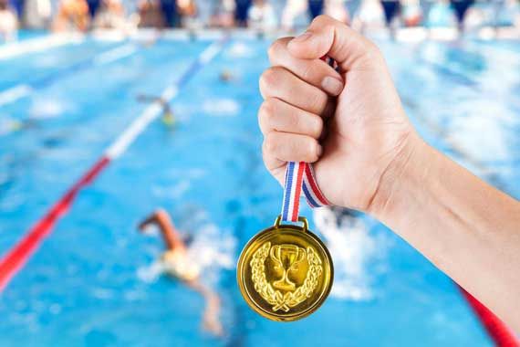 Une médaille d'or devant une piscine de nageurs.
