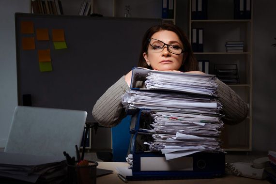 Une femme devant une pile de documents.
