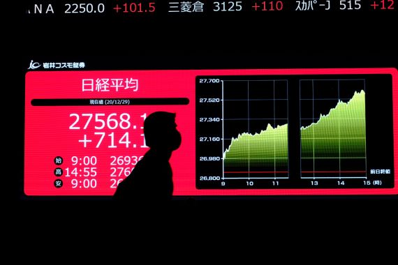 Un homme marche devant un écran qui affiche les cours de la Bourse à Tokyo.
