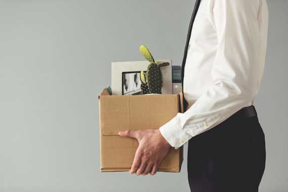 Un homme qui transporte ses effets personnels du bureau dans une boîte.