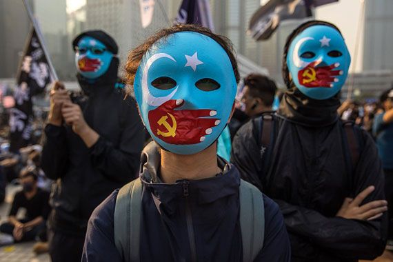 Des manifestants à Hong Kong portent des masques sur lesquels un drapeau de l'islam est oppressé par une main avec le drapeau chinois dessus.
