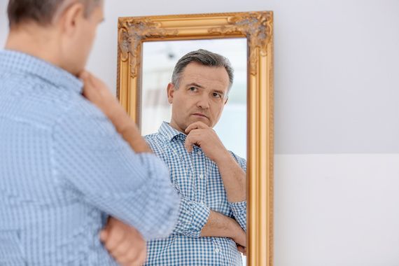 Un homme réfléchit en se regardant dans le miroir.