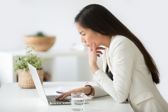Une femme consulte son ordinateur en ayant un air sérieux