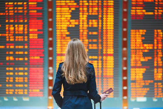Une femme devant un écran qui annonce les départs à l'aéroport.