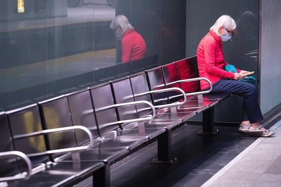 Une femme attend le métro sur un banc vide