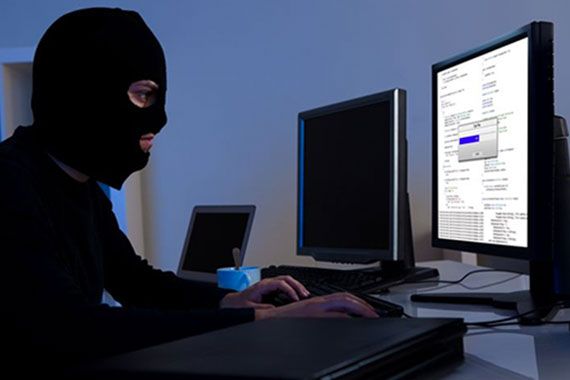 homme avec cagoule devant ordinateurs pirate informatique