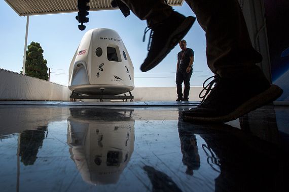 Des gens passent devant une maquette d'un vaisseau de SpaceX.