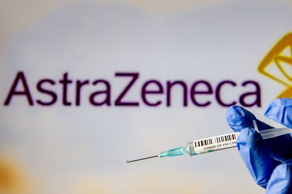 Une seringue de vaccin contre la COVID-19 devant une enseigne de l'entreprise AstraZeneca