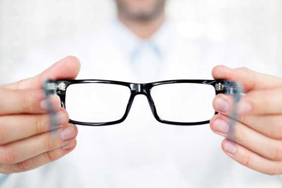 Un opticien qui tient une paire de lunettes dans ses mains.