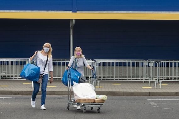 Deux femme quittent un IKEA après avoir fait leurs emplettes, un masque protecteur sur leur visage.