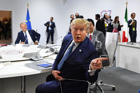 Donald Trump parle, assis, à une table entourée des dirigeants du G7.