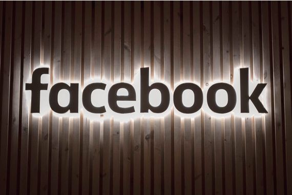 Le logo lumineux de Facebook sur un mur blanc