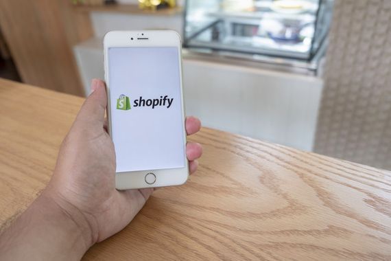 Une personne tient un téléphone sur lequel l'application de Shopify est ouverte