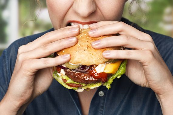 Une femme mange un burger.