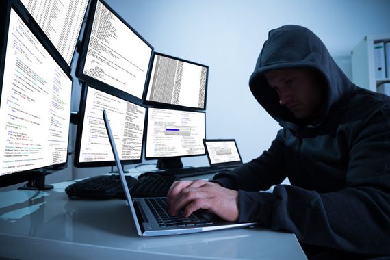 Un cybercriminel devant plusieurs écrans d'ordinateurs