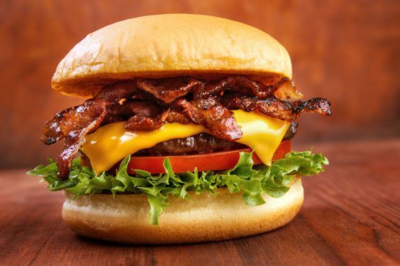 Un hamburger avec du bacon et une tranche de fromage fondu.