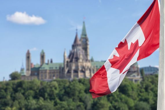 Un drapeau du Canada avec le parlement d'Ottawa en arrière-plan.