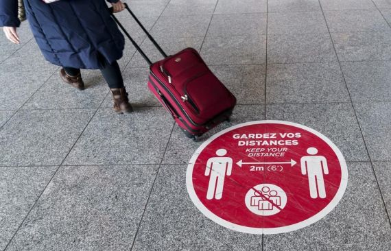 Une femme vue de dos marche avec sa valise dans un aéroport.